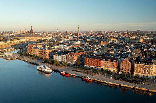 Aerial view of the historic waterfront and harbor in Copenhagen featuring traditional architecture, moored boats, and calm canal waters in Denmark.