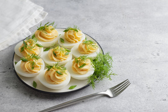 Boiled eggs stuffed with garlic and mayonnaise filling, garnished with fresh dill and green onion