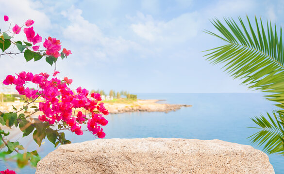 Stone as tropical empty podium with beautiful red flowers and palm leaves on blurred blue seascape background