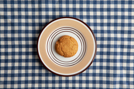 A oatmeal cookie on a blue and white checkered tablecloth