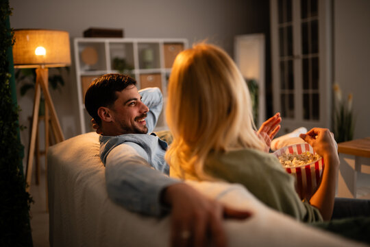 Couple enjoying movie night at home eating popcorn