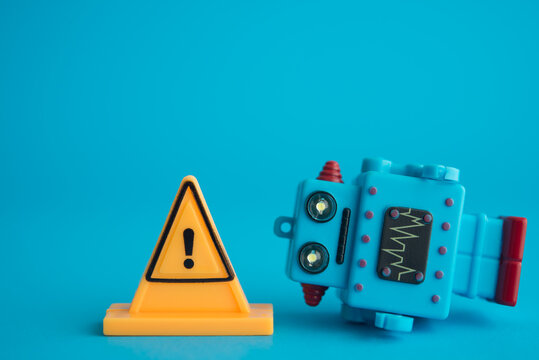 Yellow warning sign and AI robot toy on blue background with copy space. Artificial intelligence (AI) bubble, rapid speculation in stock market but low revenue and so on concept.