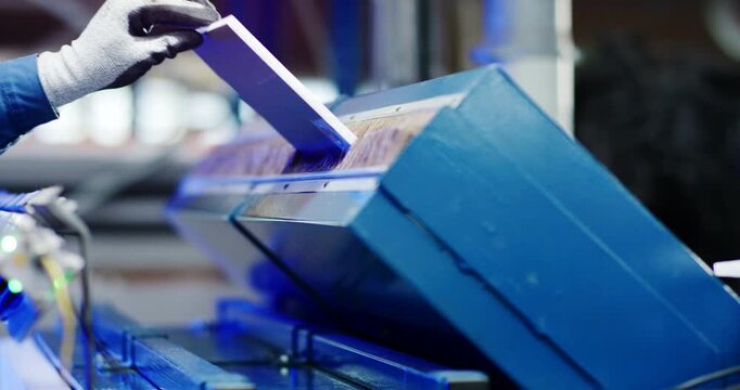 Industrial machine arm and blue frame working on a component in a factory manufacturing setting