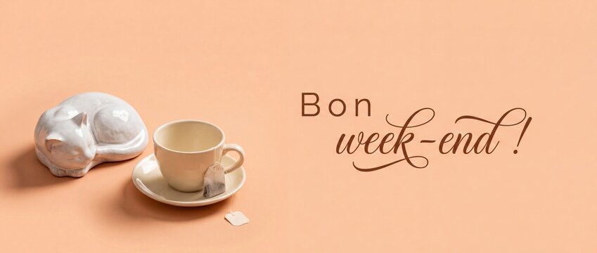Ceramic cat cup tea saucer on peach background with French text Bon week-end for cozy morning relaxation concept, minimalist banner design with decorative porcelain feline figurine, wellness greeting.