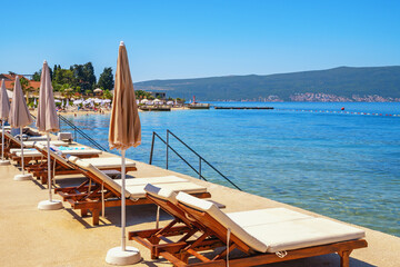 Fototapeta premium Beach vacations, chaise lounges and beach umbrellas. Montenegro, Bay of Kotor, Tivat