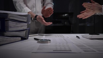 Business professionals clap hands over a cluttered desk with contracts, a magnifying glass,...