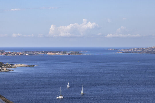 View of Capo d'Orso Mare featuring a rocky coastline, blue sea, and sailboats, with the island of La Maddalena in the distance; Capo d'Orso, Sardinia, Italy.