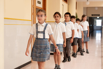 Fototapeta premium Primary School Students Walking in Line Through School Hallway