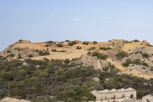 View of the historic Forte di Capo d'Orso military fortification set on a rocky hill with Mediterranean scrub and stone ruins in Capo d'Orso, Sardegna, Italy.