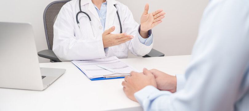 Doctor and patient having a medical consultation in a hospital room, explaining a treatment plan, discussing diagnosis, and giving advice during a medical health checkup appointment in a clinic