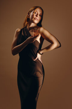 Elegant woman holding perfume bottle in black dress