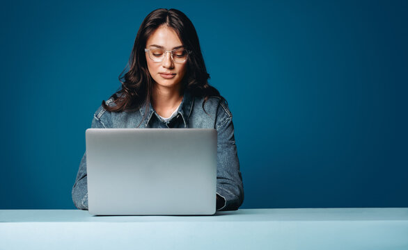 Woman working on laptop at desk in studio office setting