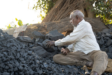 Fototapeta premium middle aged Indian villager man is working near black coal.