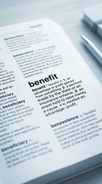 Close-up of dictionary pages defining "benefit" and related terms, symbolizing knowledge, business, and financial concepts, representative of education and finance.