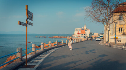 Young woman with straw hat standing by a signpost on a scenic coastal road © nhat.photograph