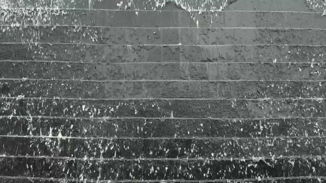 The Monolithic Descent of Monochromatic Torrent Cascading Over Sculpted Dark Stone Wall