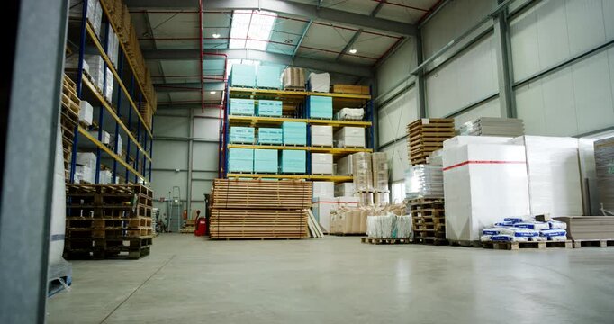 A wide view inside a large industrial warehouse with tall storage racks filled with pallets and goods