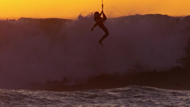 Kitesurfer crash into oncoming wave after losing board at sunset, slomo