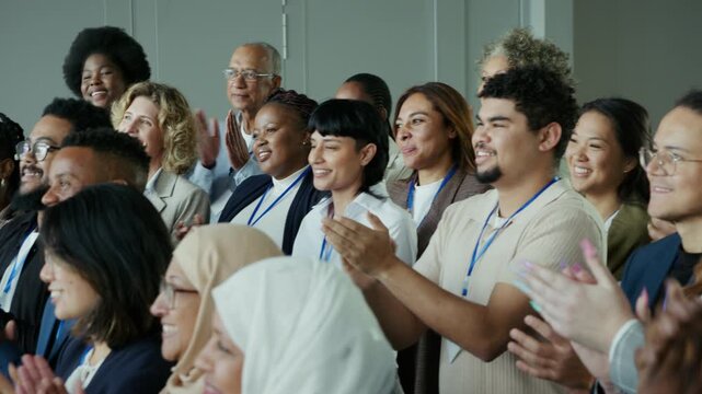 A diverse group of engaged business professionals applauds enthusiastically at a conference. The attendees express happiness and appreciation during this successful and inclusive event.