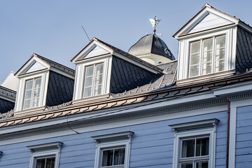 Architectural detail of elegant white attic windows built into a dark tiled roofline of a beautiful vintage wooden estate © K