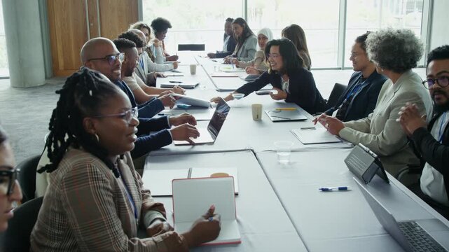 Professionals collaborate and engage in discussions around a large conference table, showcasing teamwork and focused work in a corporate setting.