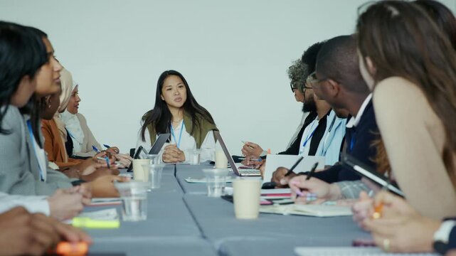 A diverse group of professionals actively participates in a dynamic business meeting, collaborating and exchanging ideas around a conference table.