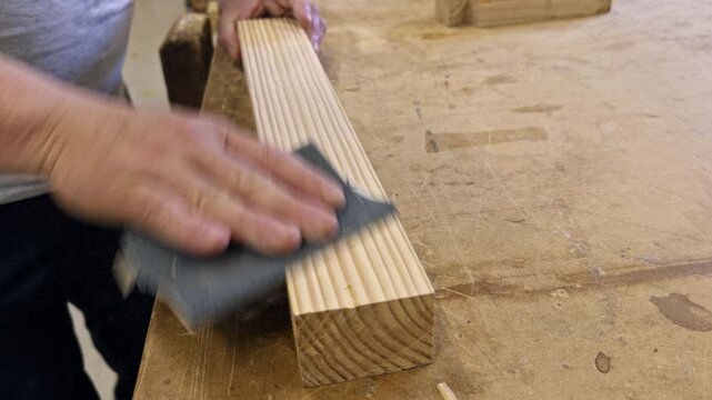 Woodworker sanding a wooden plank in workshop