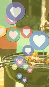 Vertical video: Man with drink grilling corn for friends, pal reaching, hearts rising covering view