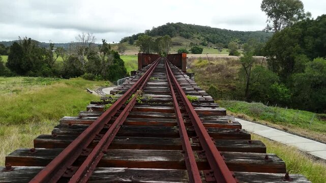 First person view travelling along a rusty old train rail bridge with with sweeping scenic country views.