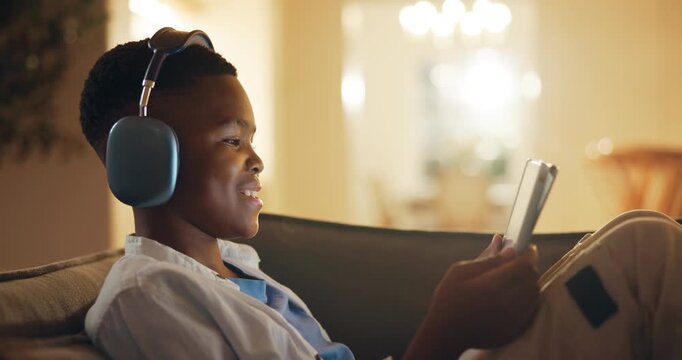 Headphones, relax and black child on sofa with tablet for online gaming, elearning or growth at night. Happy, development and boy kid with digital technology for playing game on app in lounge at home