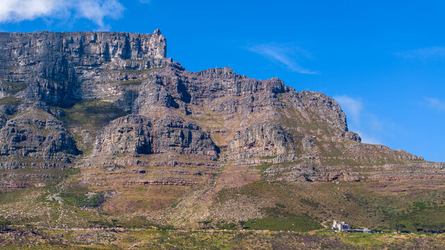 Aerial view of the rugged rock faces of Table Mountain under a clear blue sky in Cape Town, Western Cape, South Africa.