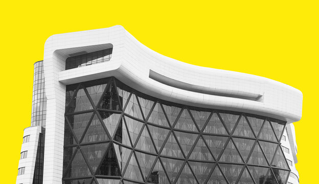 Curved modern building facade against bright yellow background. Contemporary architecture with glass atrium and geometric structure. Real estate,