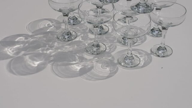 Empty champagne coupe glasses arranged on white table casting soft shadows for celebration