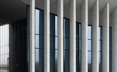 Naklejka premium Modern building facade with vertical concrete fins and dark glass windows. Minimalist architecture with clean lines and a contemporary exterior. Ideal