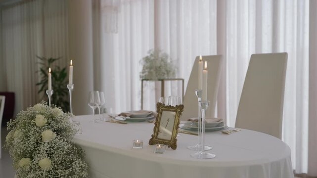 Elegant white wedding head table with lit candles flower bouquet and gold frame in bright hall