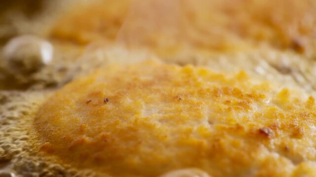 Close-up frying breaded cutlets in bubbling oil with golden crunchy crust and steam