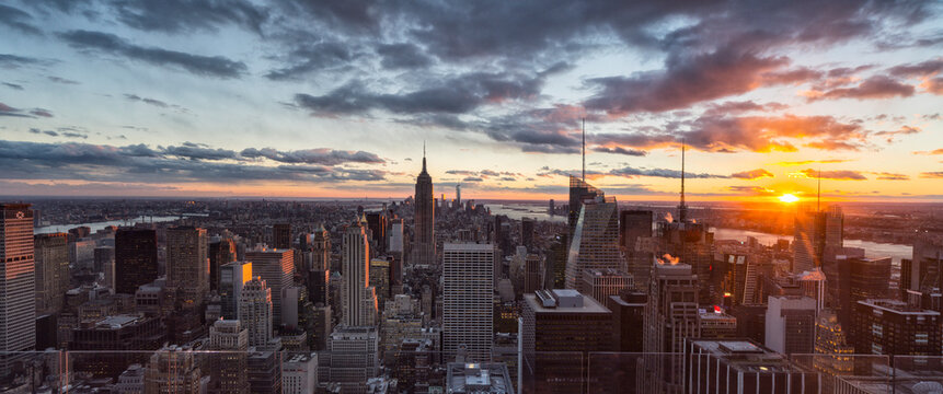 Manhattan cityscape at sunset with the Empire State Building, highlighting urban tourism and travel exploration at Top of the Rocks observatory, Rockefeller Center, New York City.