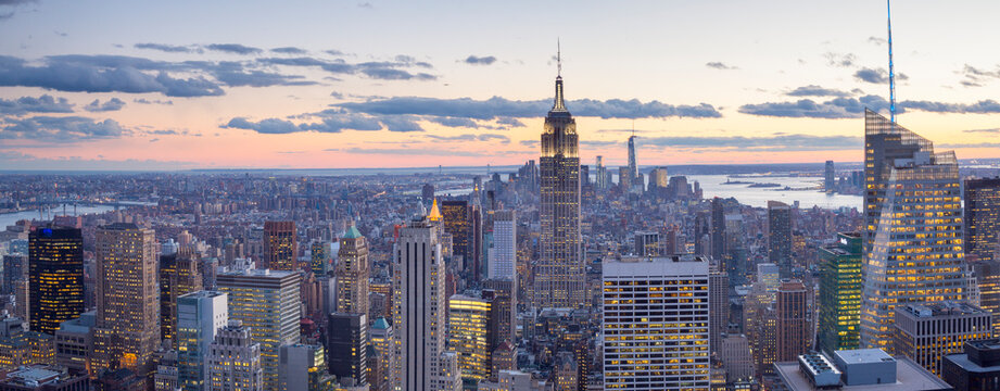 Panoramic aerial view of the Manhattan skyline and Empire State Building at twilight, showcasing an urban tourism and travel destination at Top of the Rocks observatory, Rockefeller Center, NYC.