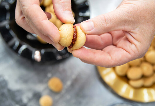 Close up of woman hands holding freshly baked cookie with guava jam filling. Tasty homemade cookies. Food preparation. Food photography.