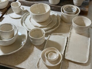 Handmade ceramic dishes with cups, plates, and bowls displayed on a table at a crafts fair