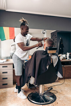 Professional African American barber cutting client hair in a modern barbershop