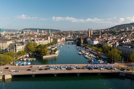 Aerial view of the Limmat River flowing through the historic city center of Zurich with a tram crossing the bridge and boats moored along the banks in Zurich, Zurich, Switzerland.