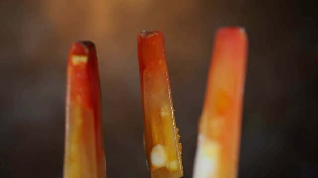 4K Video of Delicious Homemade Fruit Popsicles with Fresh Orange and Strawberry Pieces Melting Slowly in a Row Against a Dark Studio Background, Perfect Commercial Visual for Summer Refreshment