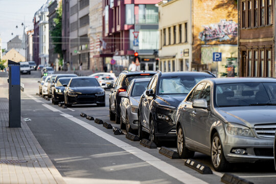 Vehicles parked in designated street parking zones along an urban thoroughfare, representing city automotive lifestyle, transport infrastructure, and traffic