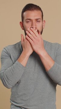 I will not say anyone. Frightened Lebanese young man closing mouth with hand, looking intimidated scared at camera, gestures no, refusing to tell terrible secret unbelievable truth on beige background