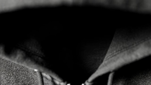 Pulling camera showing hooded torso shifting in studio to reveal zipper pull, drawstrings shadow