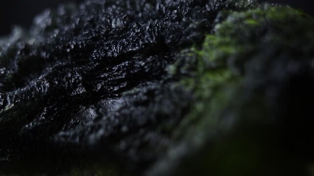 Moldavite gemstone extreme close up zooming motion. Precious tektite from the Czech Republic. Green jagged alien surface texture. Sculptation