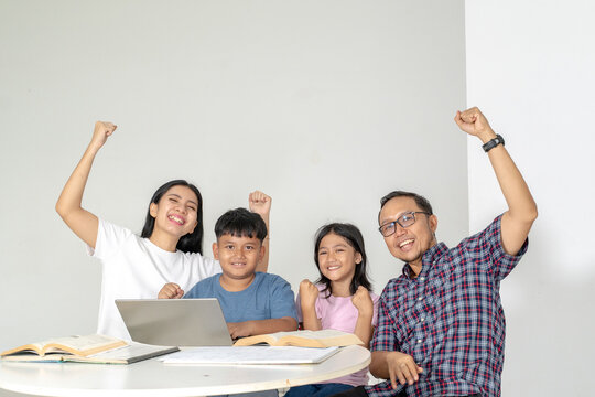 Happy Asian Family Celebrating Success While E-Learning with Laptop at Home
