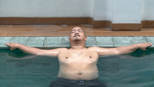 Overweight Asian Man Relaxing and Floating in Swimming Pool, Wellness Concept