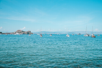 Obraz premium Sailboats Anchored in Turquoise Sea Near Corfu Old Fortress